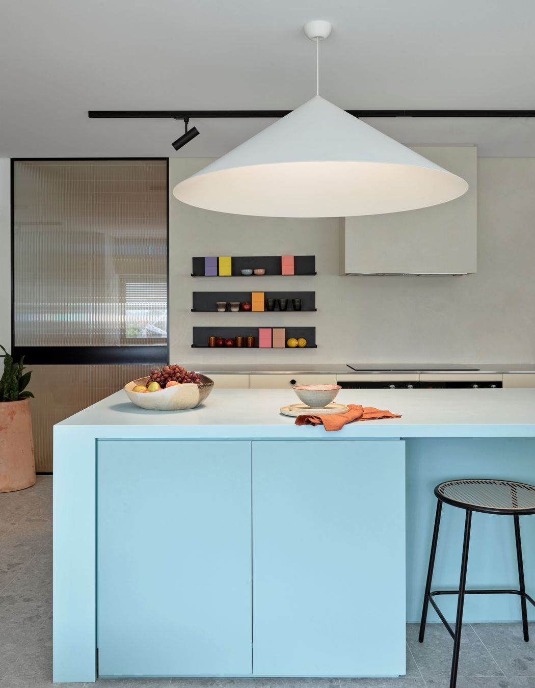 The kitchen combines strong shapes with soft, pastel colours to create a homely yet robust space for the staff to cook and eat.