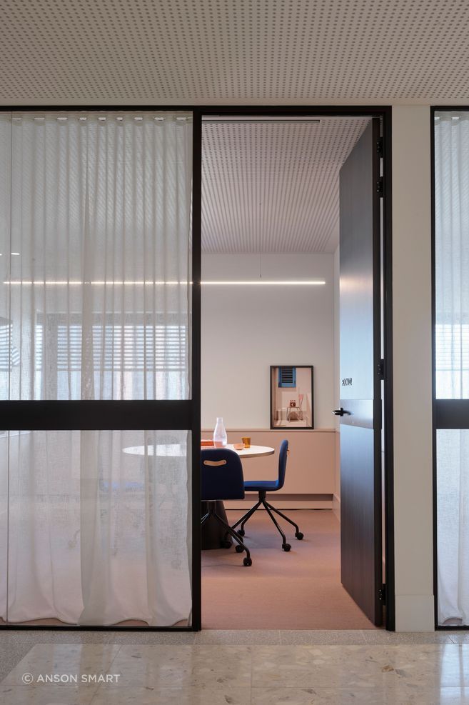 A meeting room is softened with pastel colours, sheer curtains and beautiful photographic art.