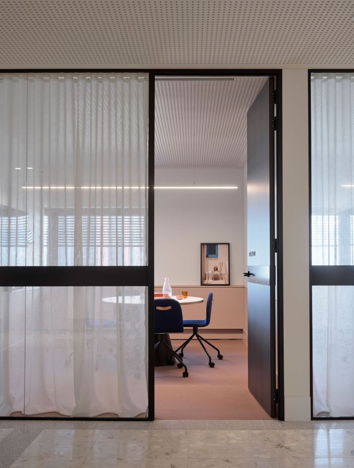 A meeting room is softened with pastel colours, sheer curtains and beautiful photographic art.