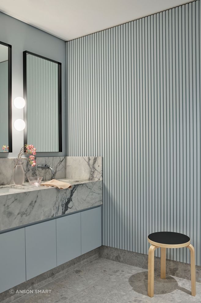 The soft ribbing in the wall panelling contrasts against the marble vanity in the bathroom.