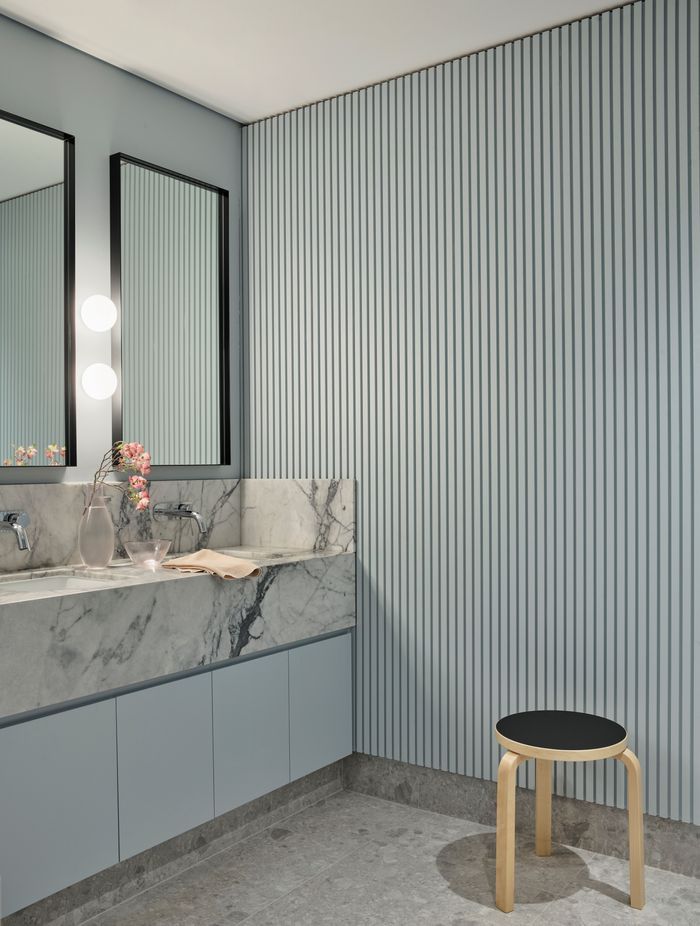 The soft ribbing in the wall panelling contrasts against the marble vanity in the bathroom.