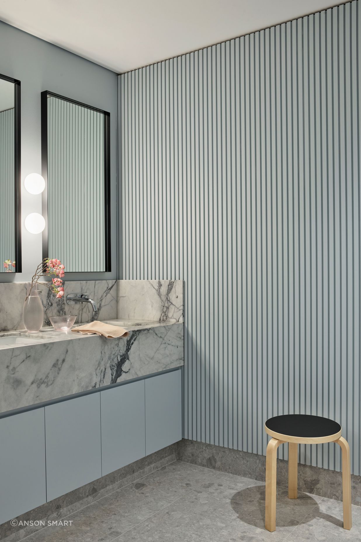 The soft ribbing in the wall panelling contrasts against the marble vanity in the bathroom.