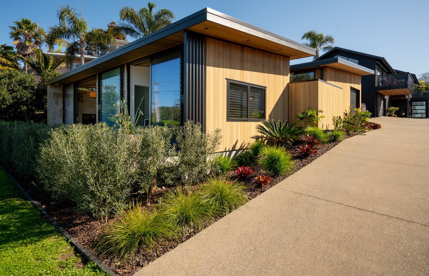 Cedar cladding backdrops the landscaping, echoing a beachside bach aesthetic.