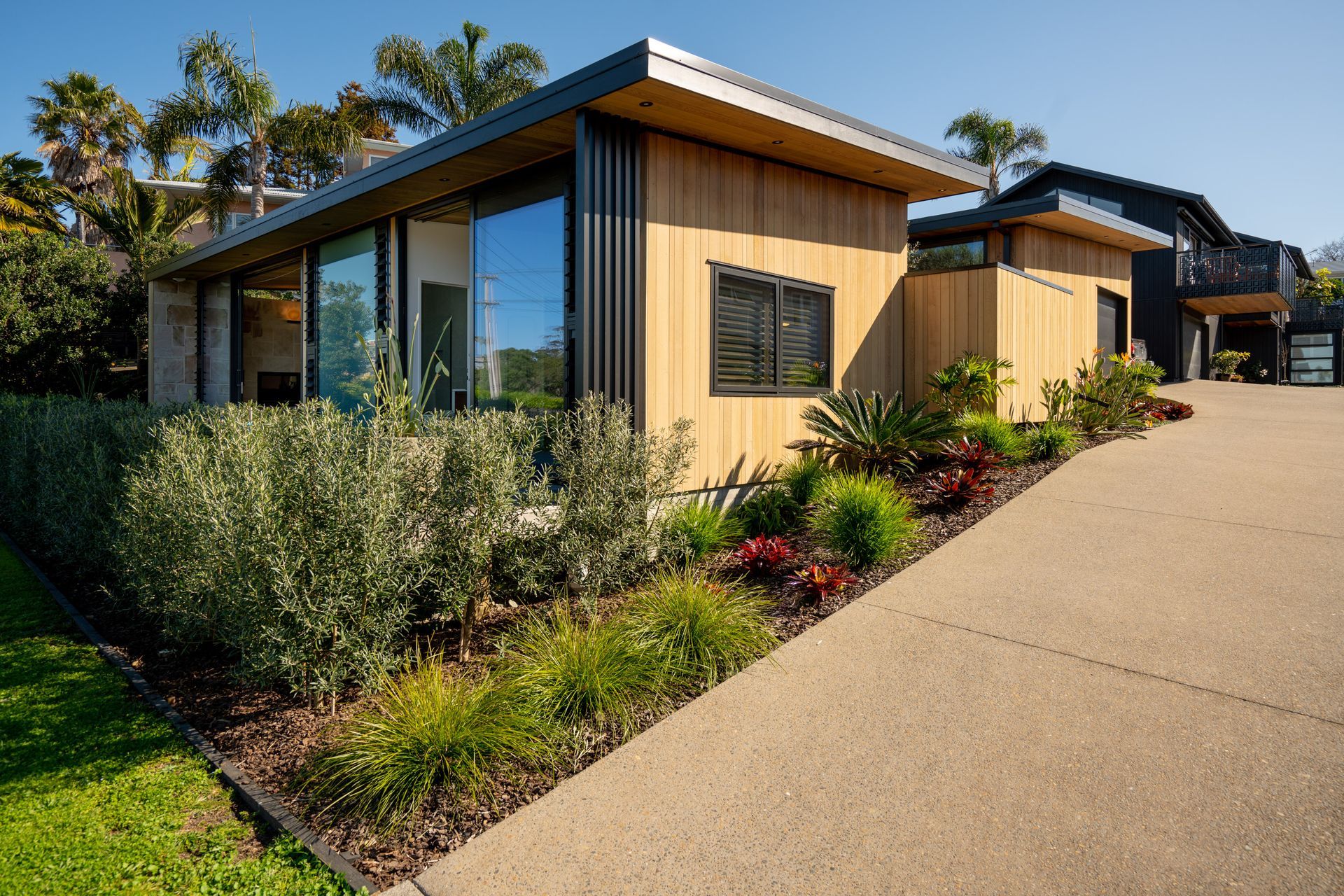 Cedar cladding backdrops the landscaping, echoing a beachside bach aesthetic.