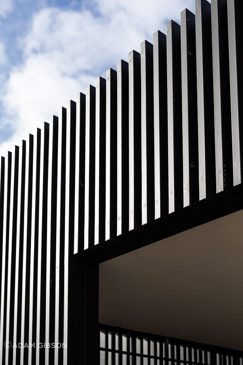 The vertical timber slats and boards contrast with the warmth of the stone.
