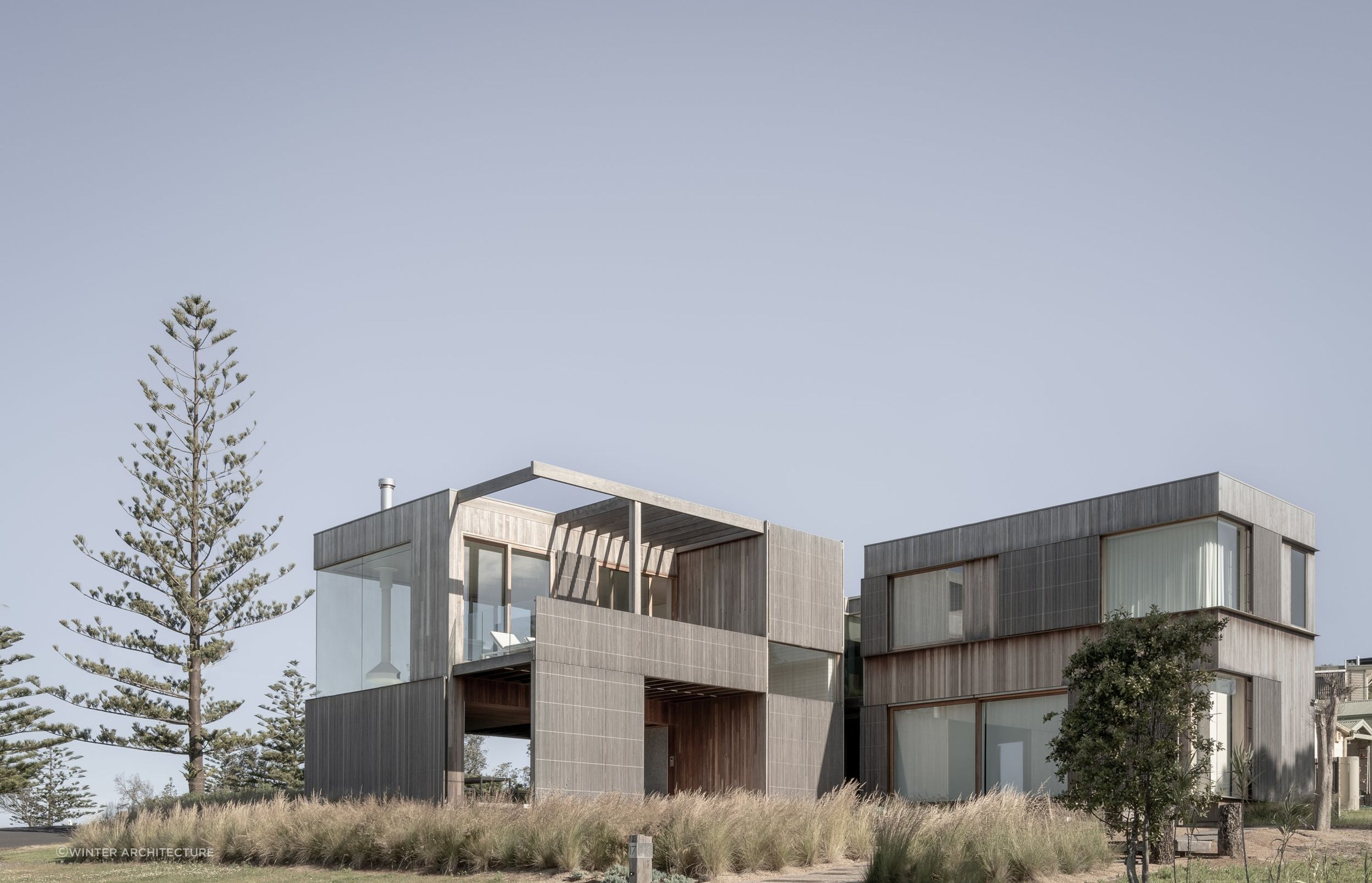 The striking weathered timber cladding and dune-like landscaping reflect the Bergamui Beach House's rugged setting.