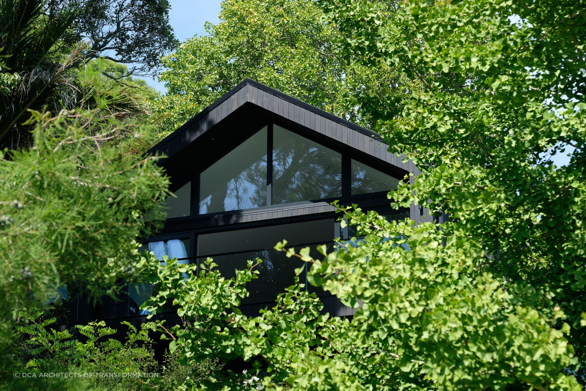The gabled roof profile peaks out among lush surroundings.