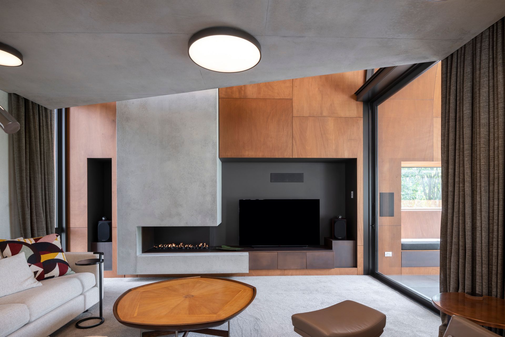 In the den, the cabinetry under the TV is copper. The fire is a custom-made Eastside Niche by Living Flame, and the carpet is Bremworth Valour Luxe, and furniture was custom-made by David Shaw.