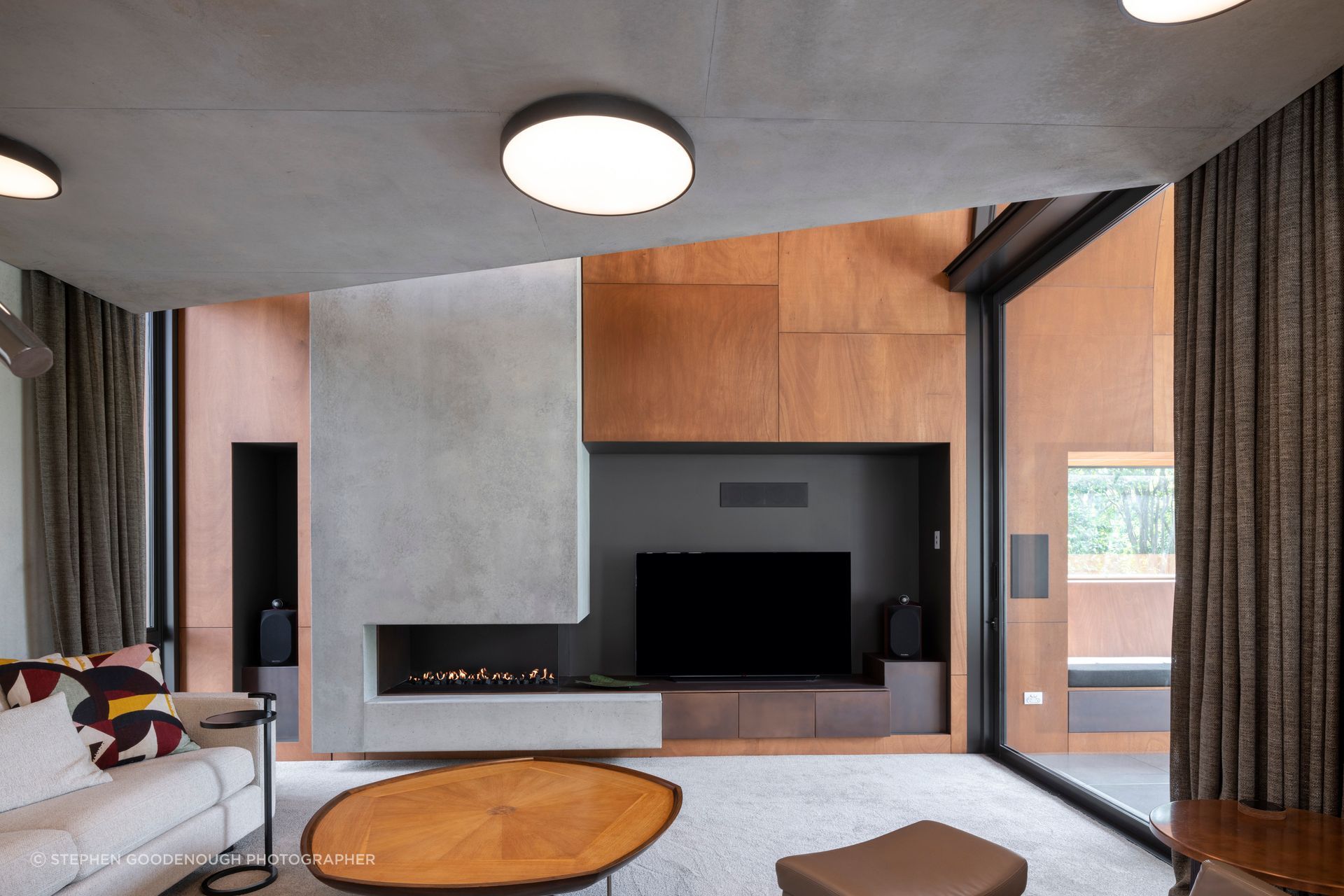 In the den, the cabinetry under the TV is copper. The fire is a custom-made Eastside Niche by Living Flame, and the carpet is Bremworth Valour Luxe, and furniture was custom-made by David Shaw.