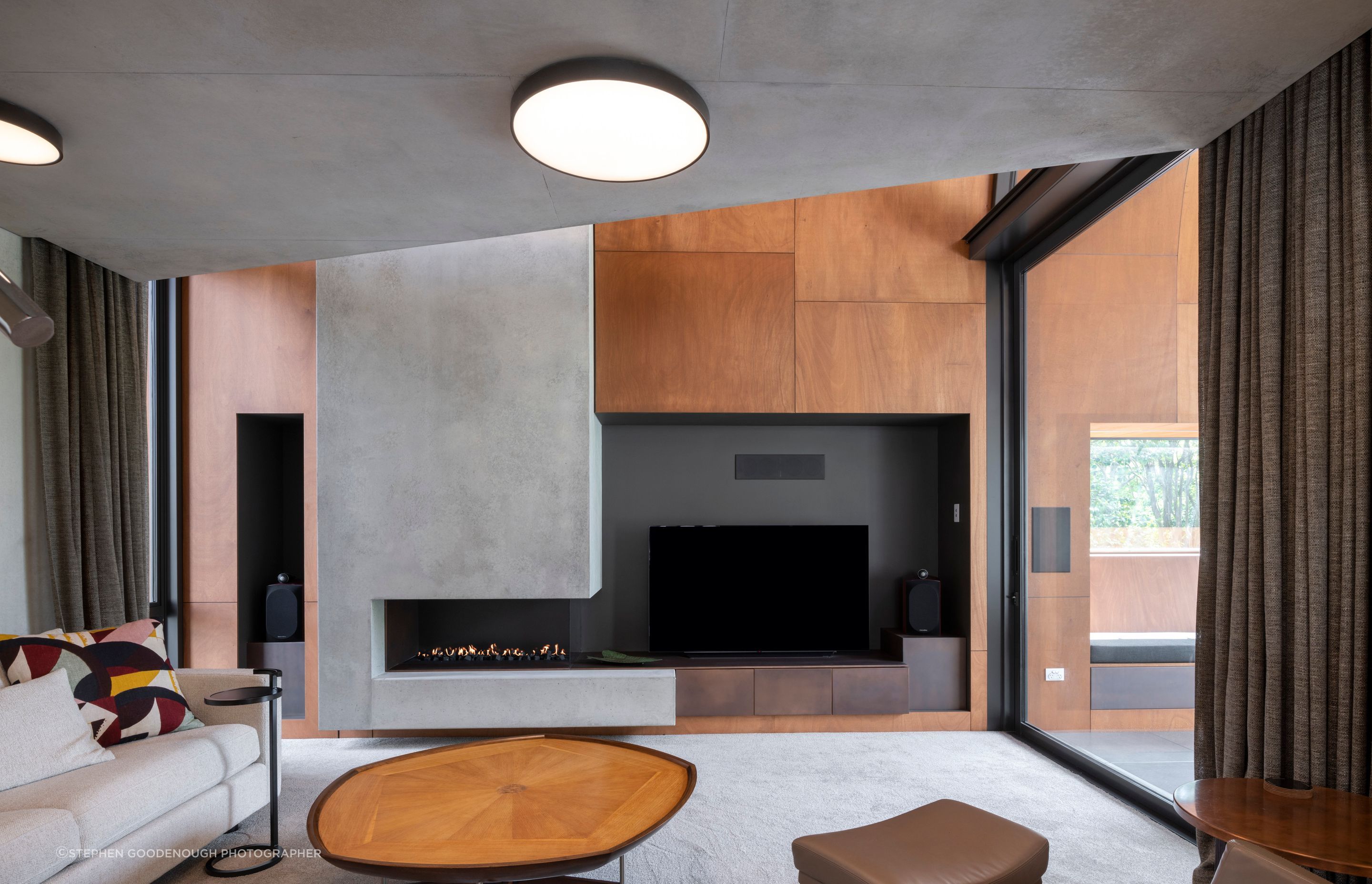 In the den, the cabinetry under the TV is copper. The fire is a custom-made Eastside Niche by Living Flame, and the carpet is Bremworth Valour Luxe, and furniture was custom-made by David Shaw.