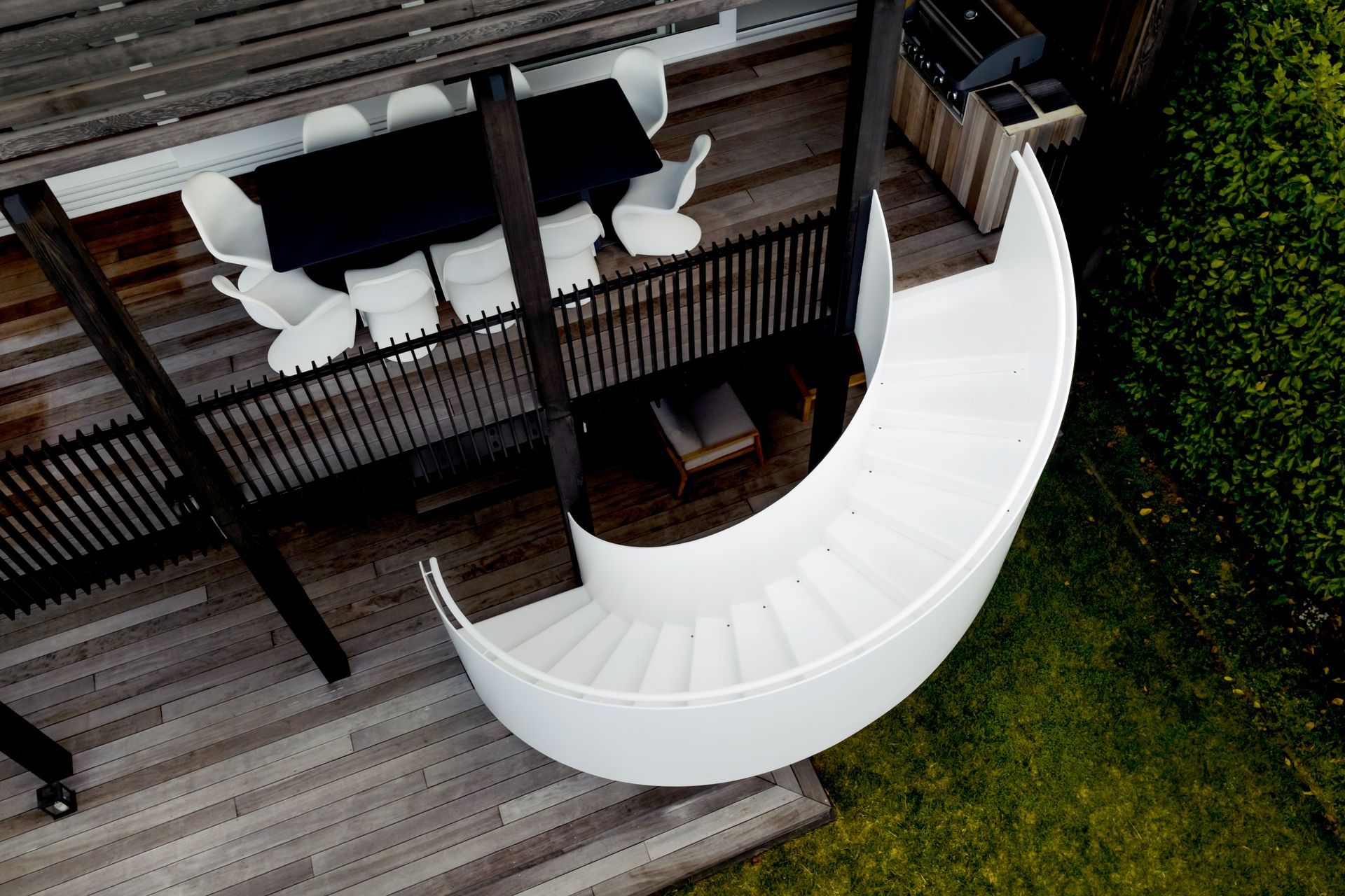 The dramatic white spiral stair contrasts against the darker exterior elements.