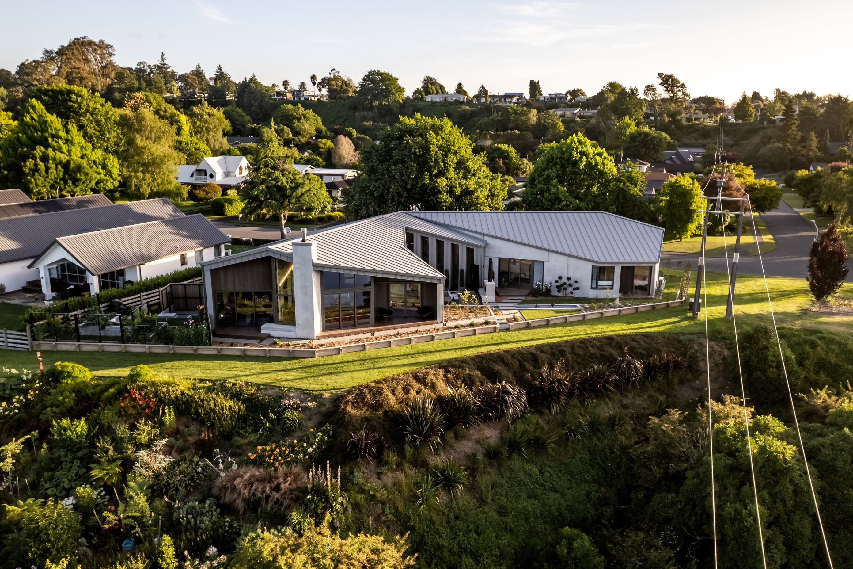 Seen from above, the sculptural form of the home hugs the landscape, drawing in the light and the views, while creating privacy from the street and neighbours.