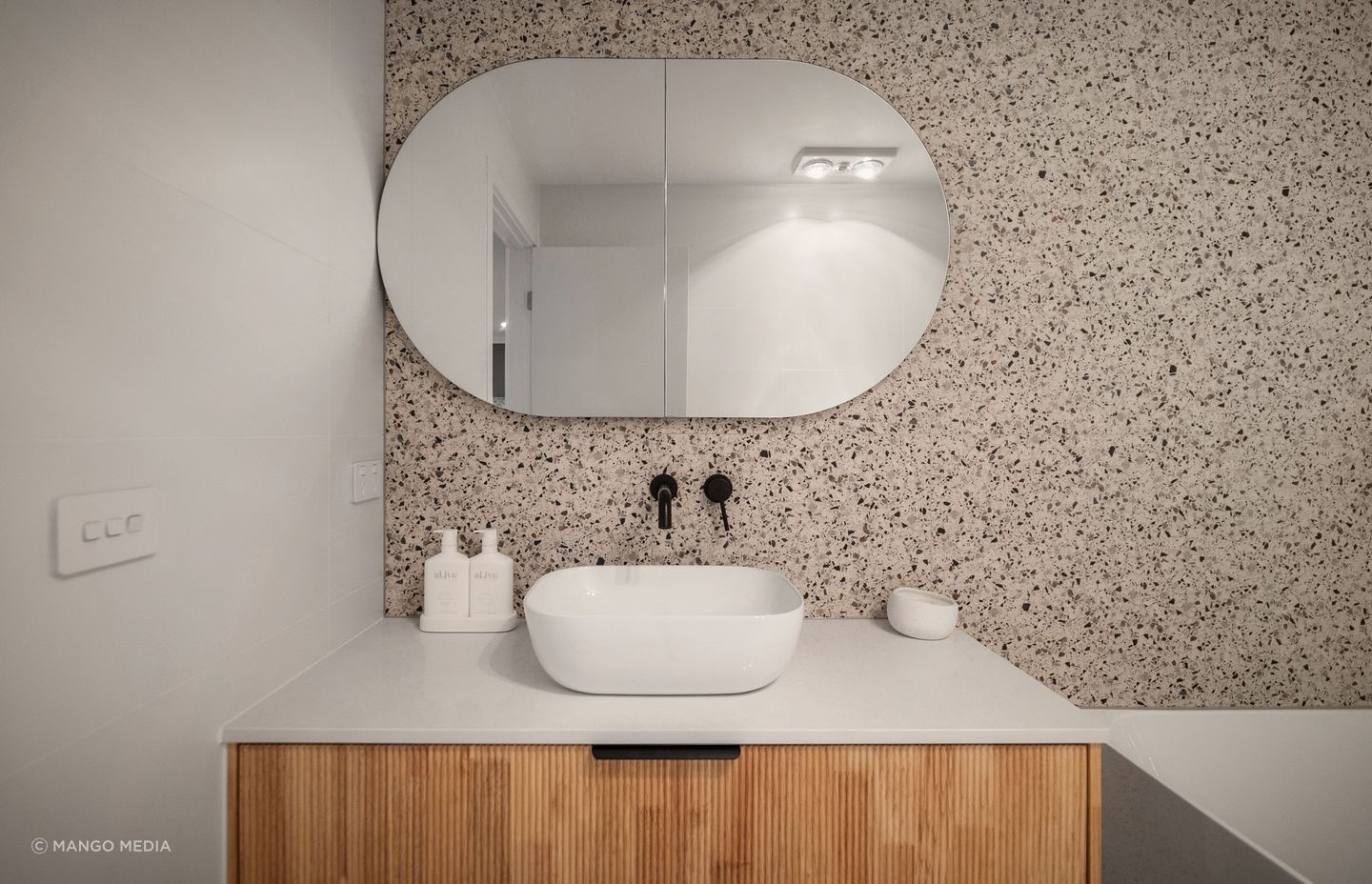 The earthy palette and inclusion of curves continues in the main bathroom.