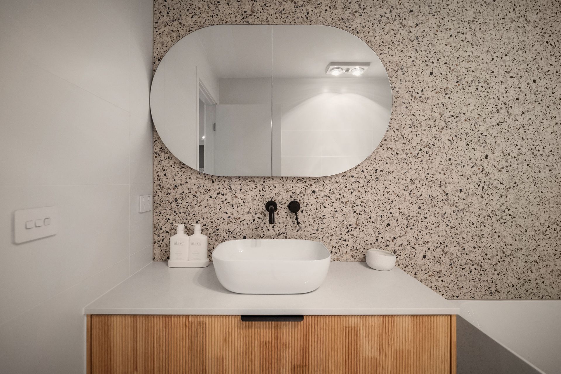 The earthy palette and inclusion of curves continues in the main bathroom.