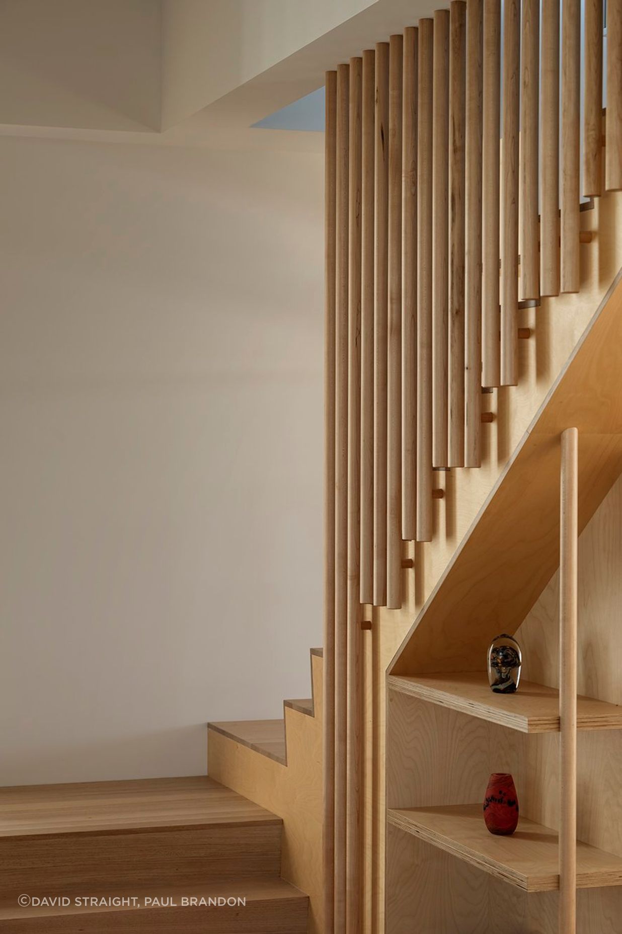 An open staircase leads up towards a second bedroom, bathroom, and multi-purpose space with a kitchenette.