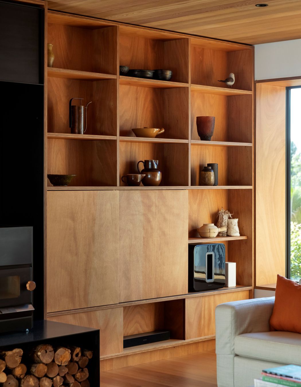 Timber bookshelves in the sitting area with sliding panels concealing a TV. “I was keen to use natural finishes and avoid paint wherever possible,” says Hamish.