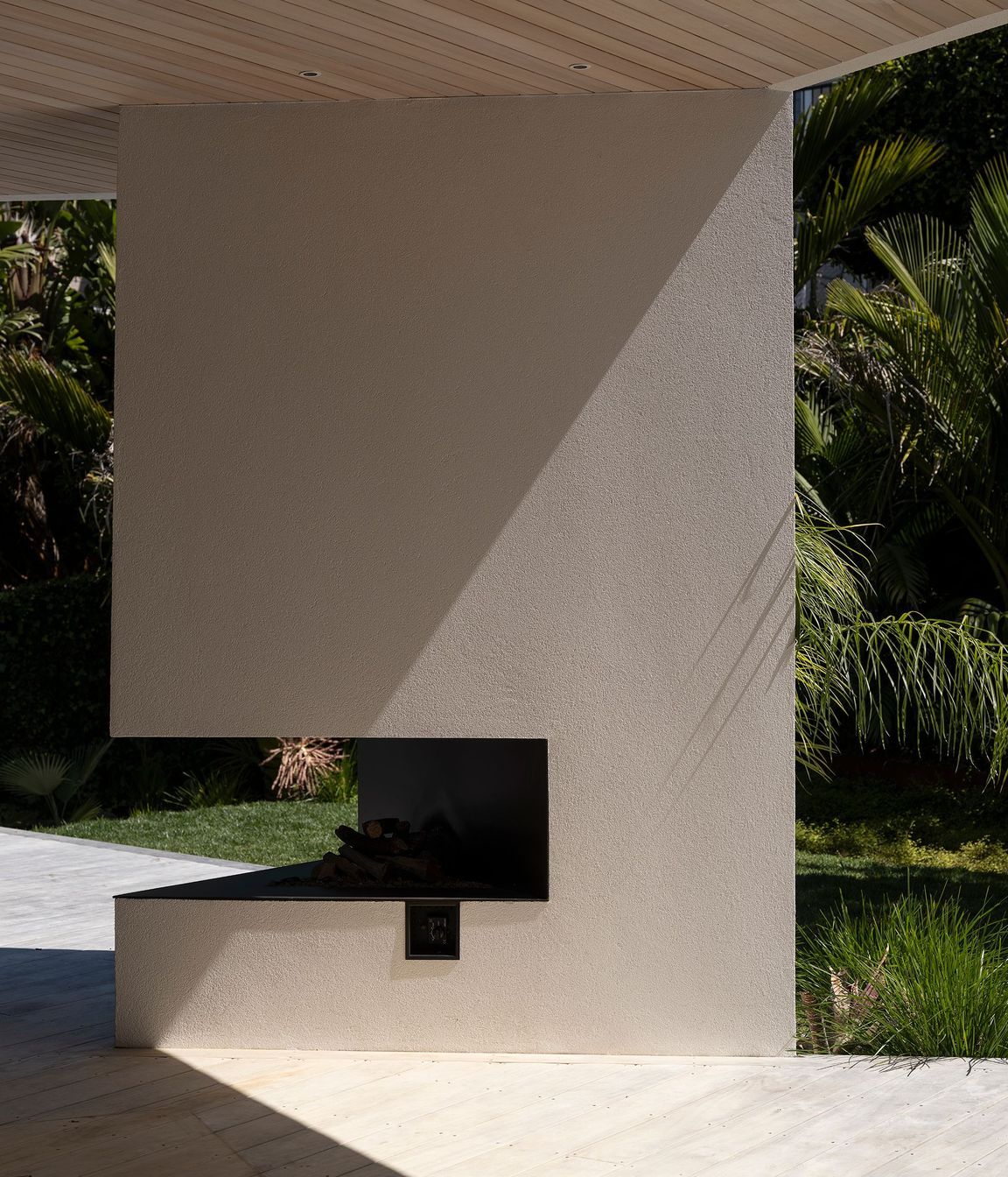 The irregular triangle design of the outdoor fireplace showcases the beauty of the crisp plaster finish.