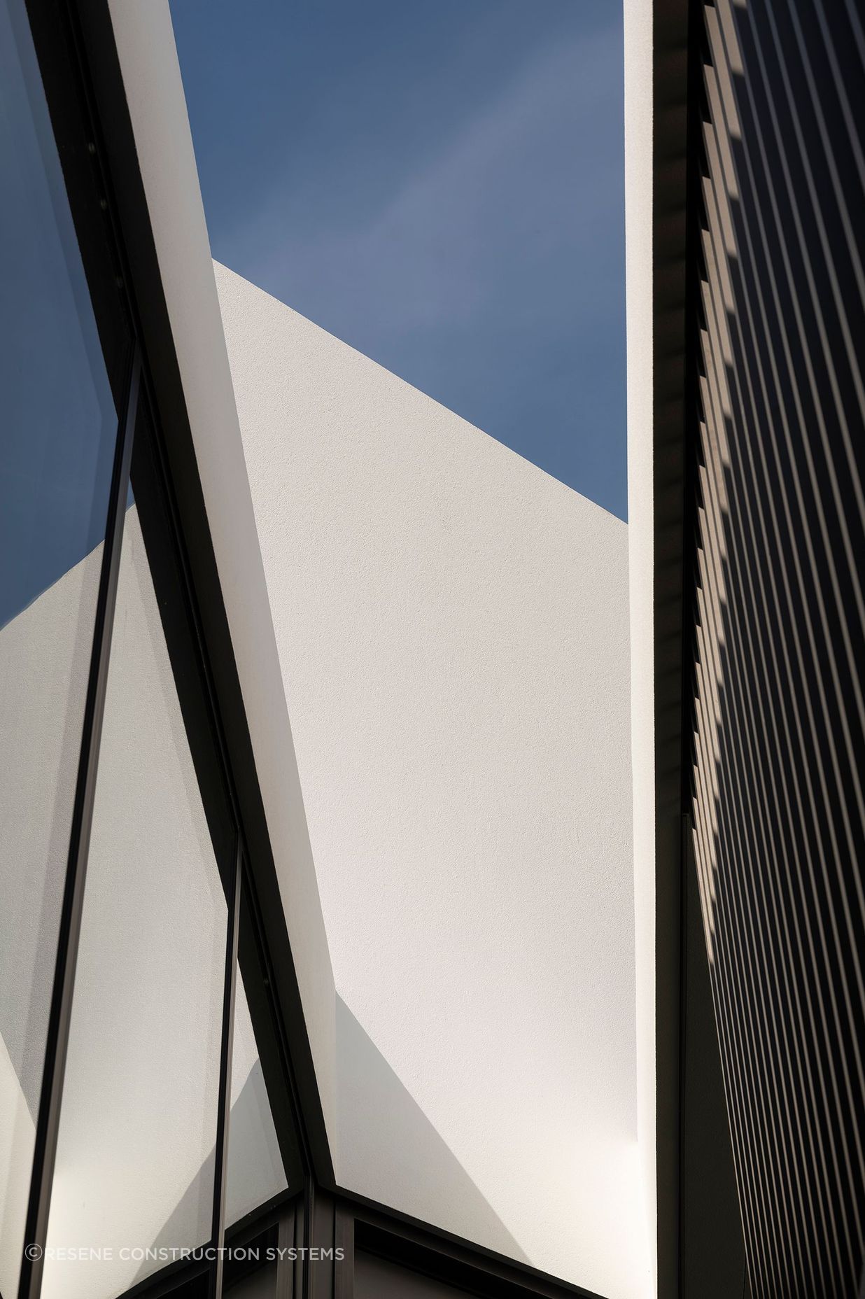 The shadows from the cedar fins are beautifully reflected by the glass and as shadows on the plaster surfaces, creating a constant play of light and shadow.