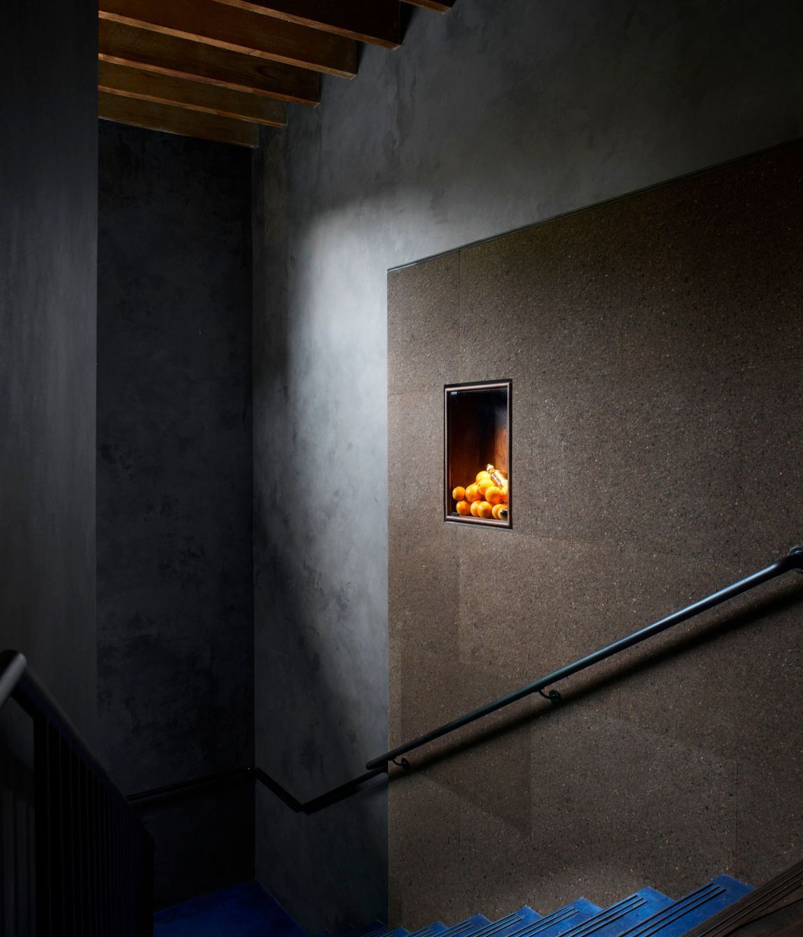 Clad in charcoal Portuguese cork panels, the staircase wall leading to the Gin Lab provides acoustics and internal advertising needs in one, thanks to its pin-able surface.