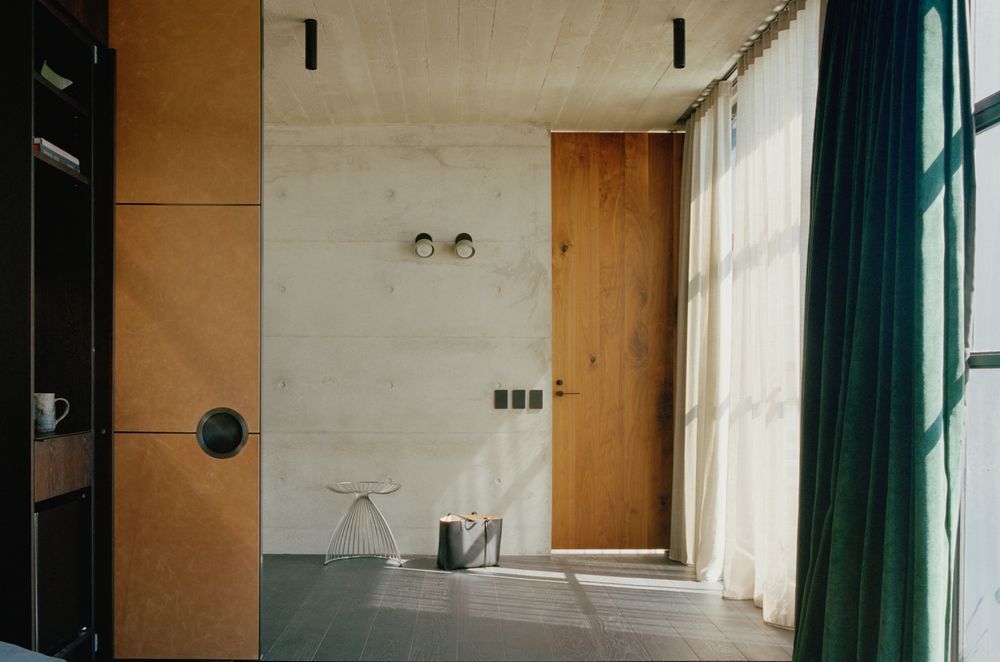 The interior of the tower form celebrates the rawness of off form concrete and contrasts it against warm walnut veneer and rich green velvet curtains.