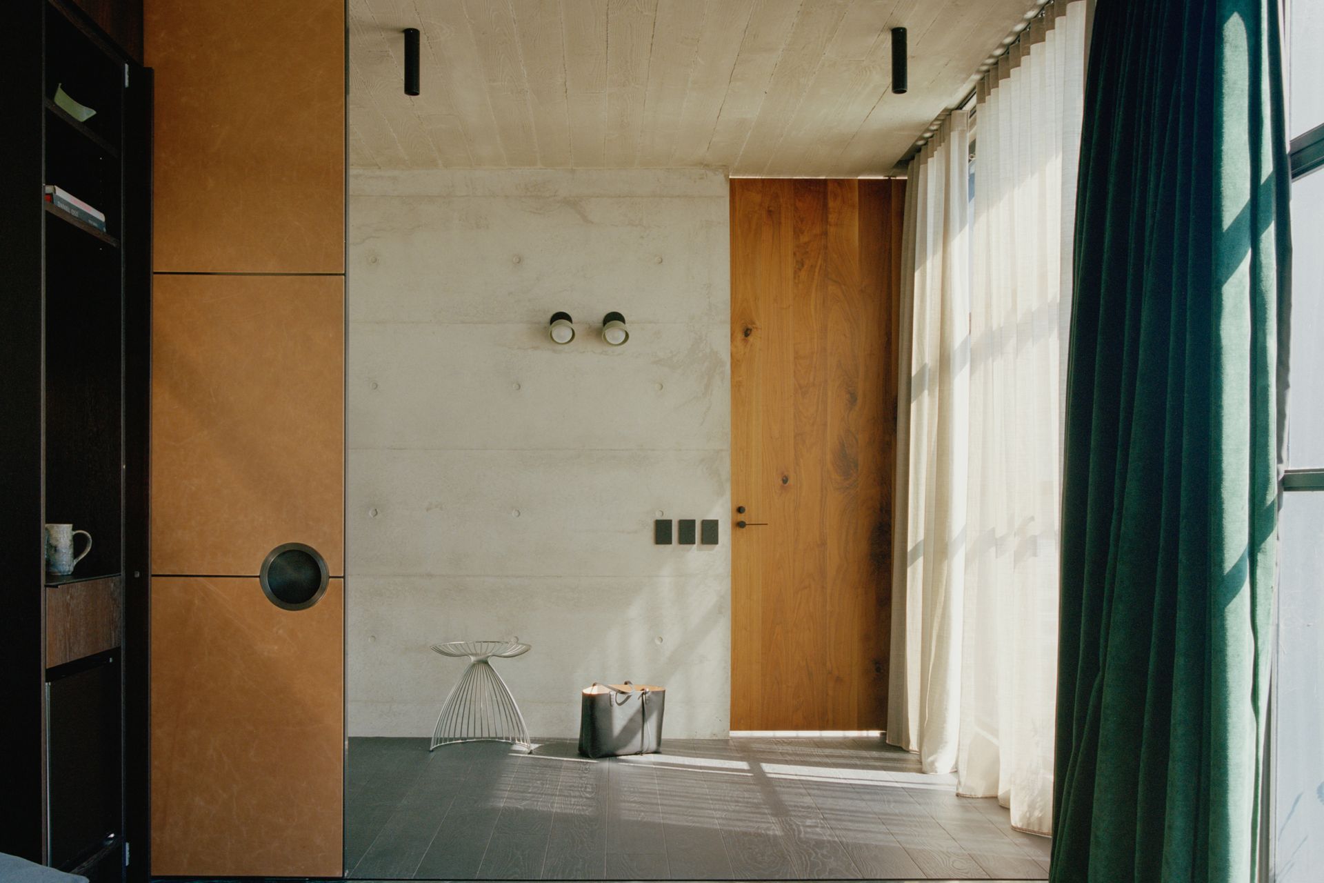 The interior of the tower form celebrates the rawness of off form concrete and contrasts it against warm walnut veneer and rich green velvet curtains.