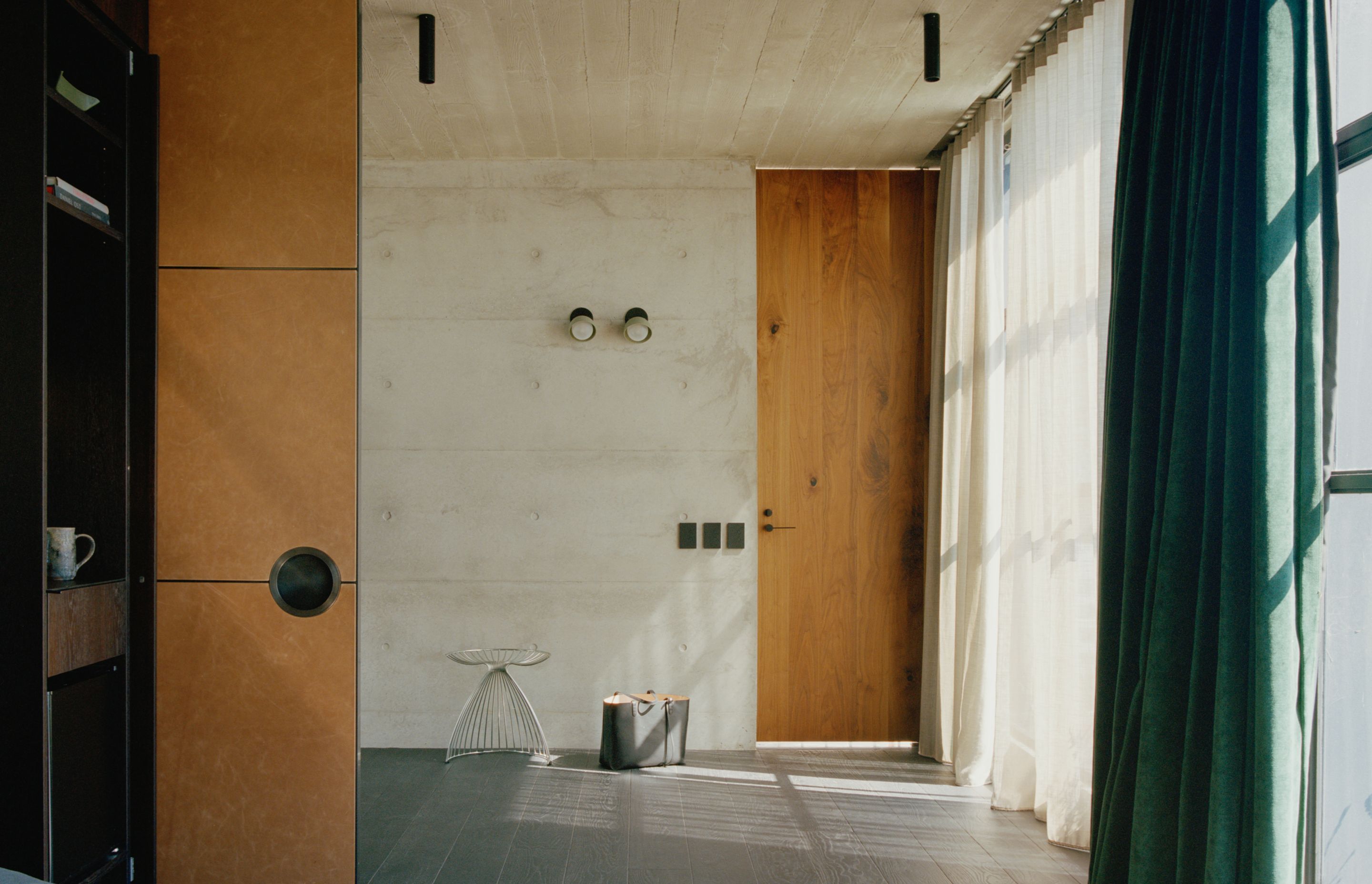 The interior of the tower form celebrates the rawness of off form concrete and contrasts it against warm walnut veneer and rich green velvet curtains.