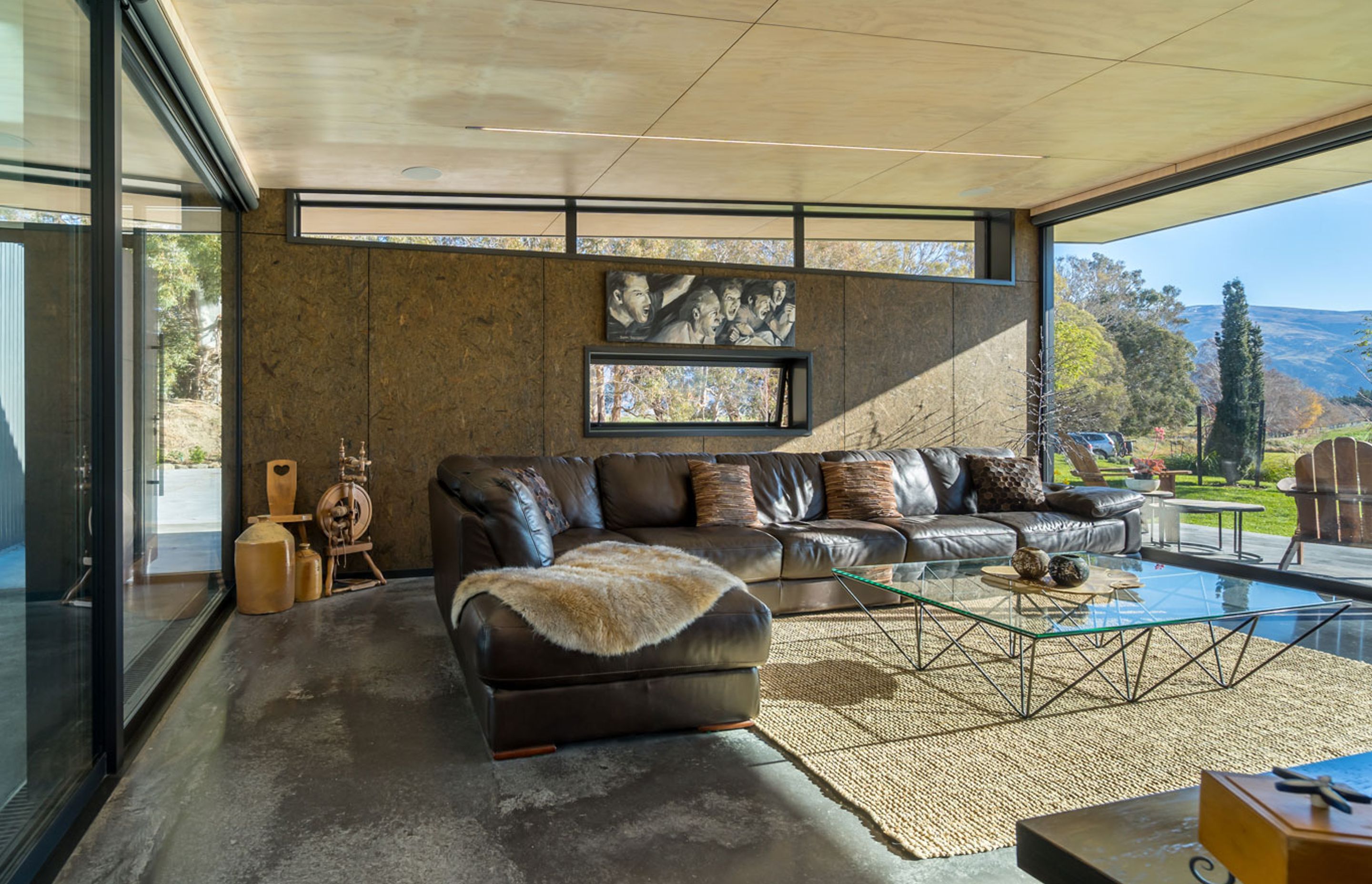 The spinning wheel was Sue’s mother’s, and the painting by a friend depicts the excitement of watching a game. “That’s what goes on in our lounge,” says Sue. The textured wall is strandboard, which blends with the landscape.