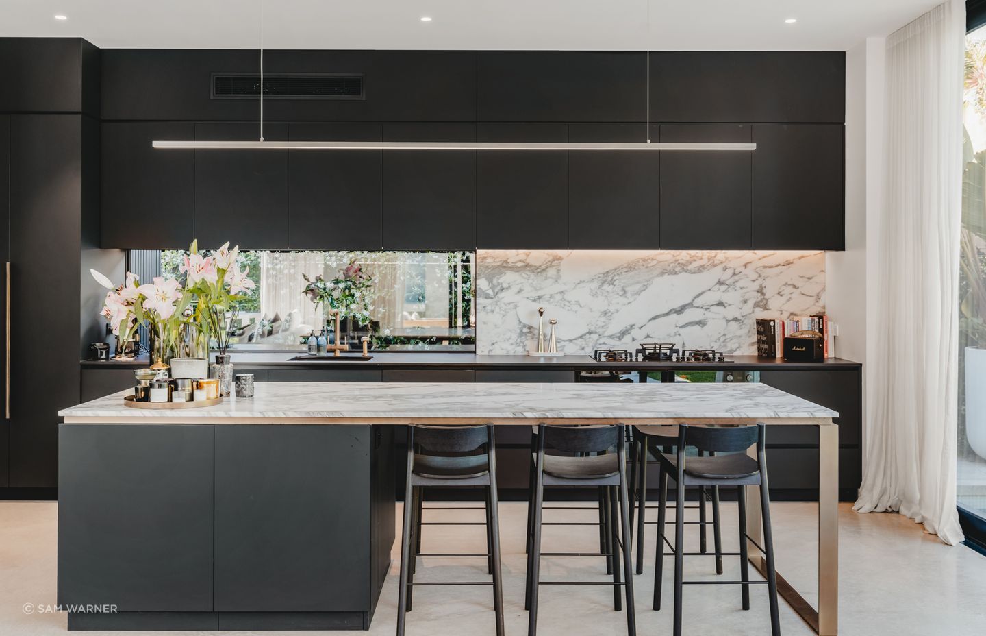 The dramatic kitchen combines traditional marble with dark cabinetry.