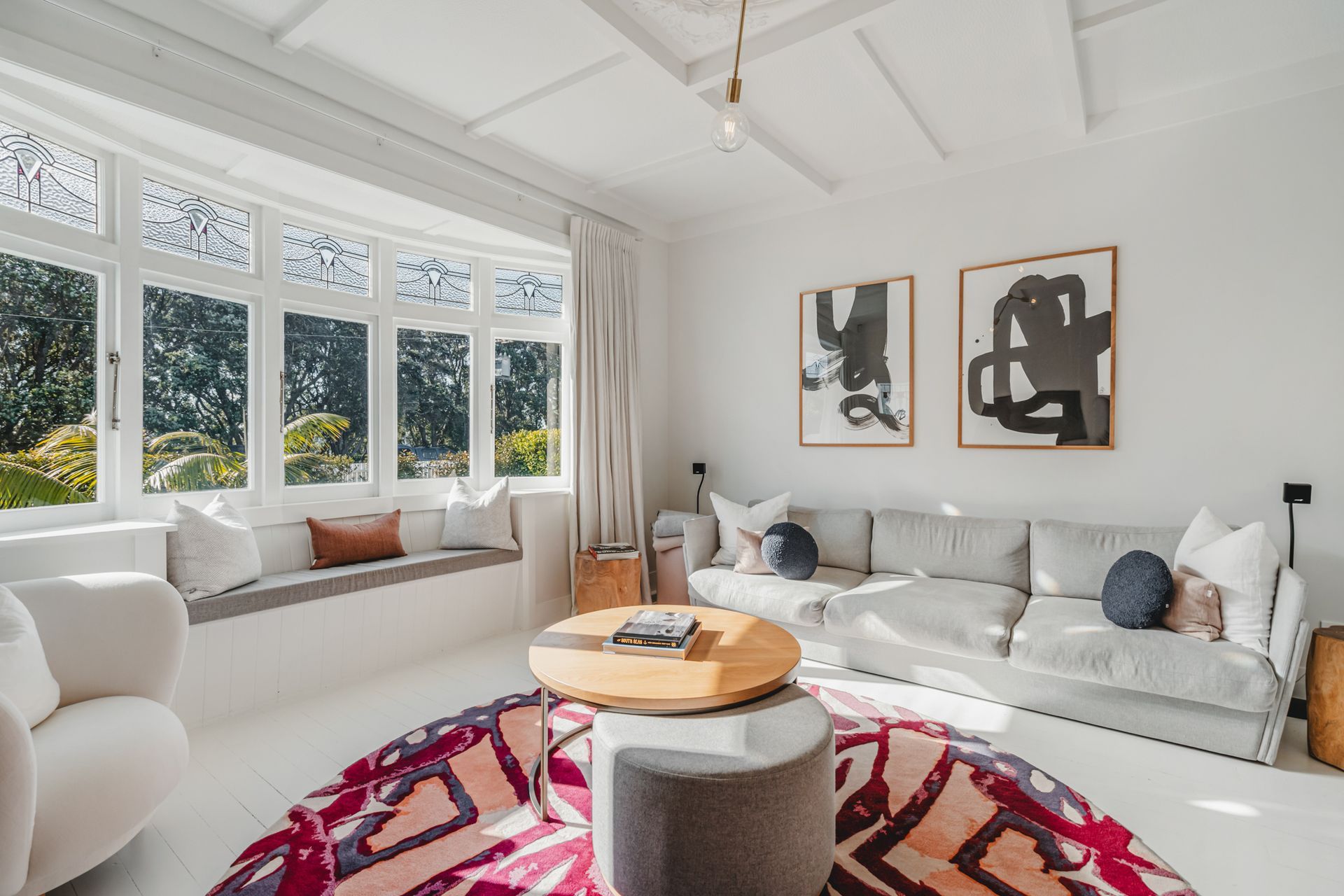 The original bay window at the front of the house was retained, and the white space is elevated with a bold rug and artwork.