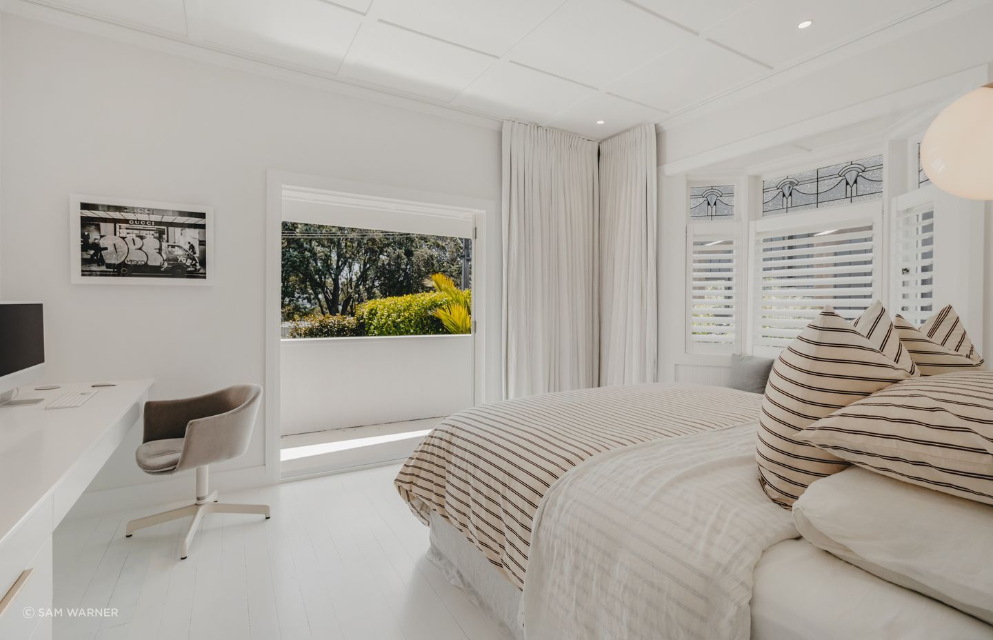 The master bedroom now features a built-in office space and floor-to-ceiling drapes.