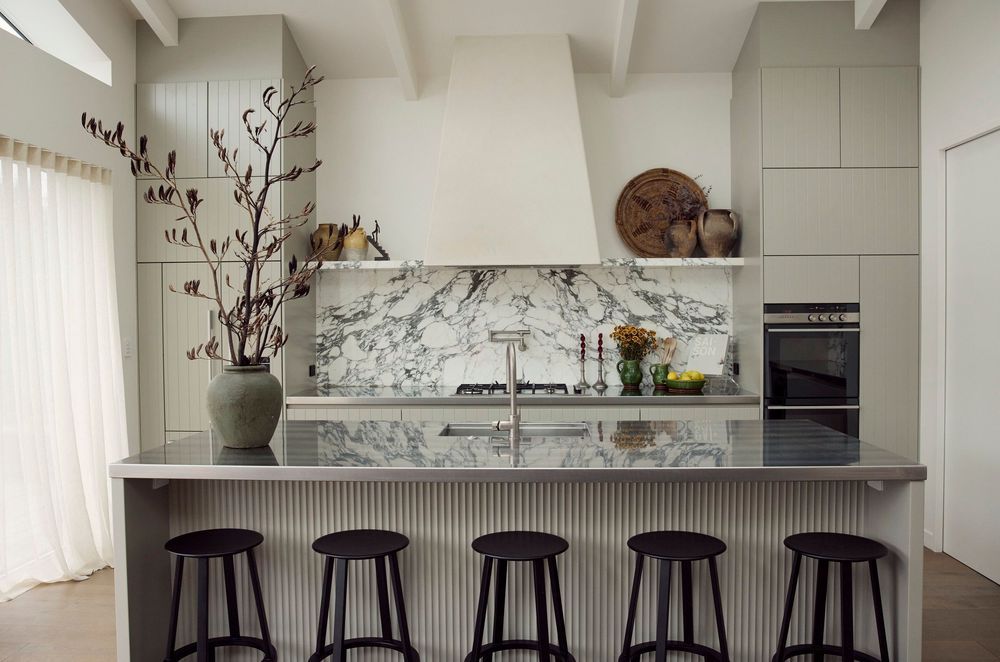 With appliances and storage relegated to the walls, a large island bench offers space for food prep and casual meals without cutting communication between the chef and others using the space.