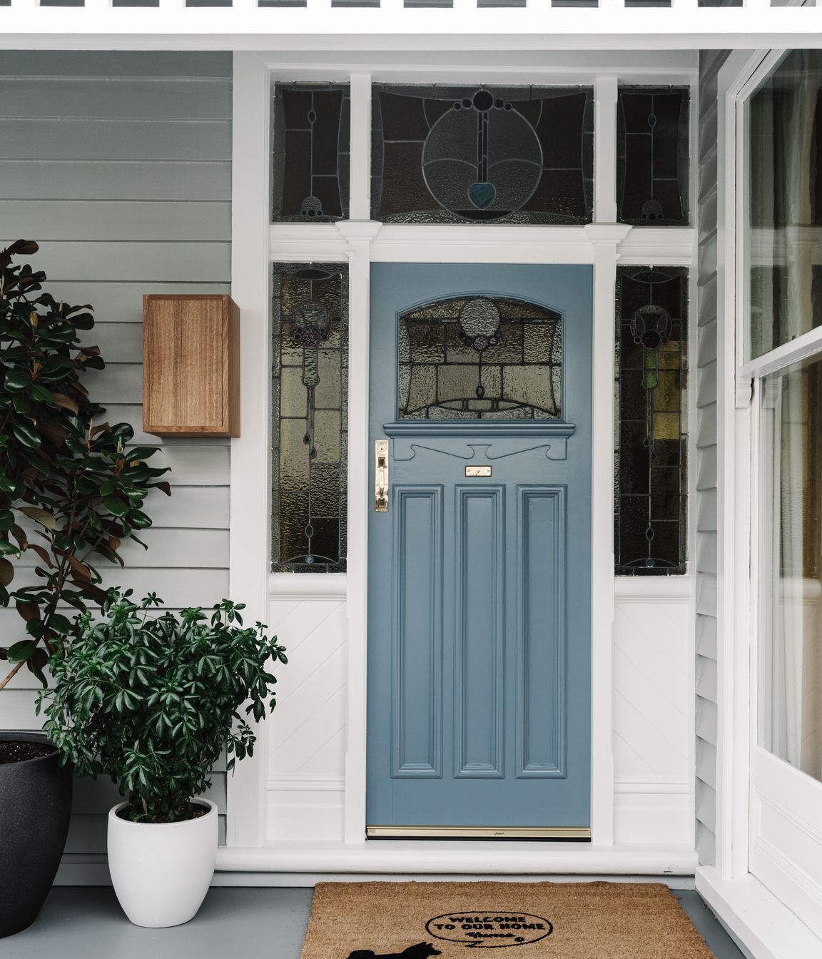 The original front door with stained glass has been refreshed with a coat of pale French blue paint.