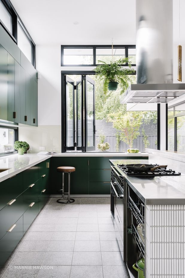 The kitchen island workspace is stainless steel with custom steel rack draws providing easy access to pots and pans. The rest of the joinery is 2pac dark green with a Dekton glacier benchtop.