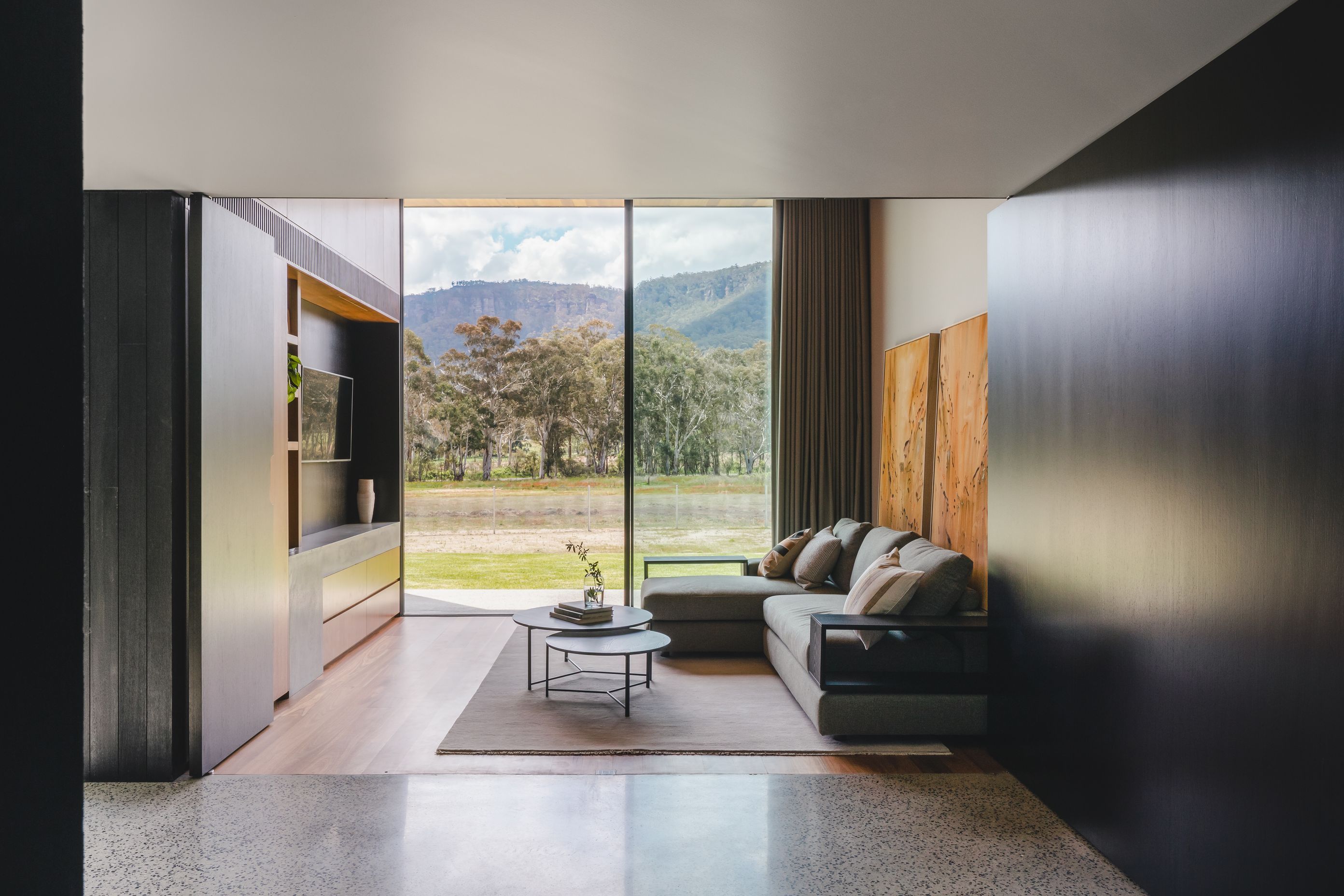 Floor to ceiling glass captures the dense bushland and mountains.