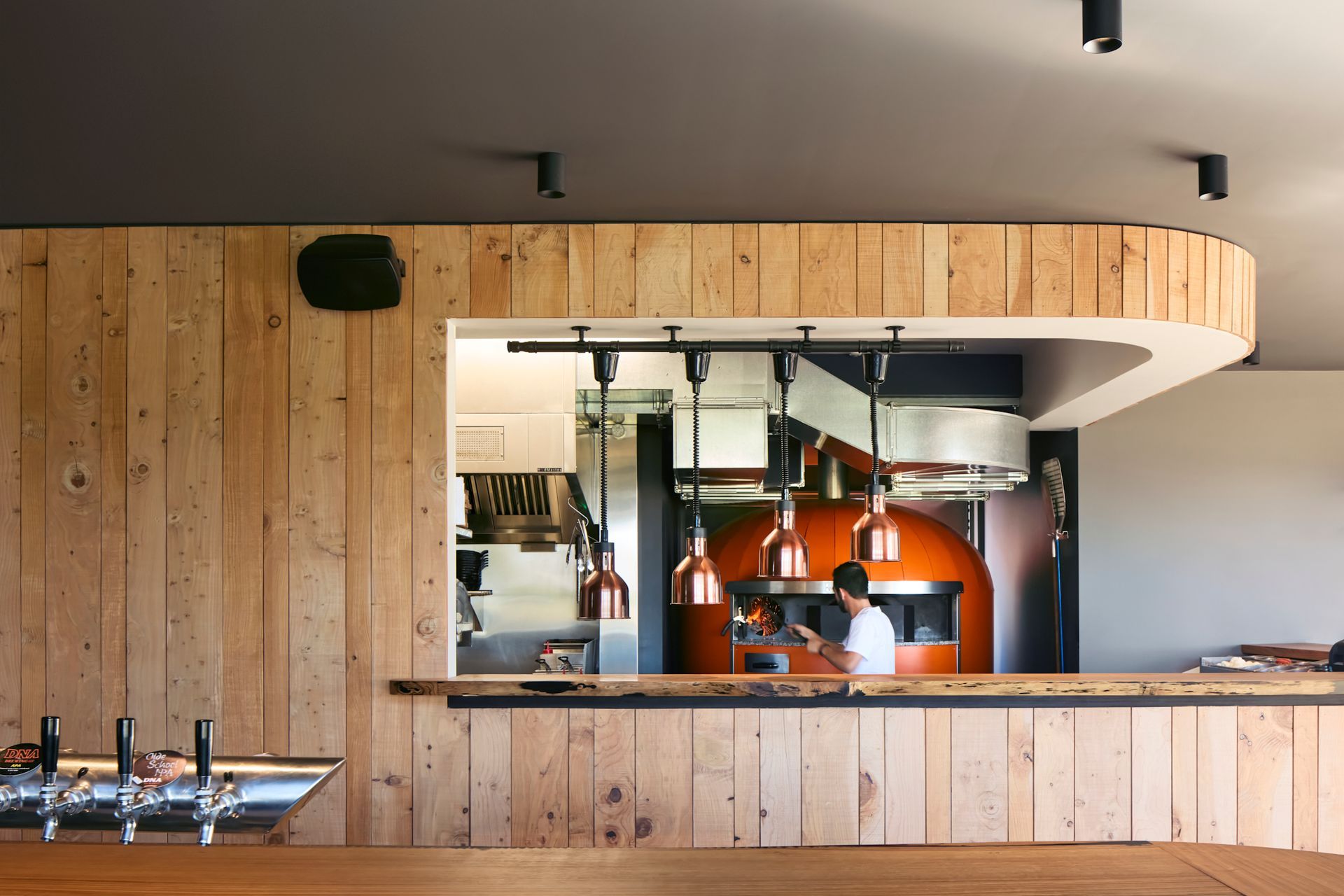 The commercial kitchen is on display, framed by Himalayan cedar panelling felled on the client's farm.