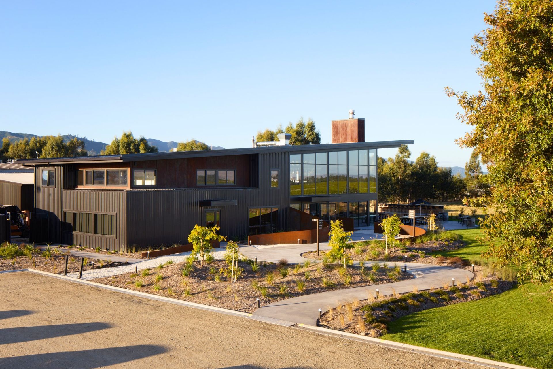 A two-storey, rectangular form meets a long, monopitched roof and an industrial chimney. A meandering path winds up towards curved Cor-Ten steel walls, referencing the braided patterns of the land whilst revealing different perspectives of the surrounding vineyards.