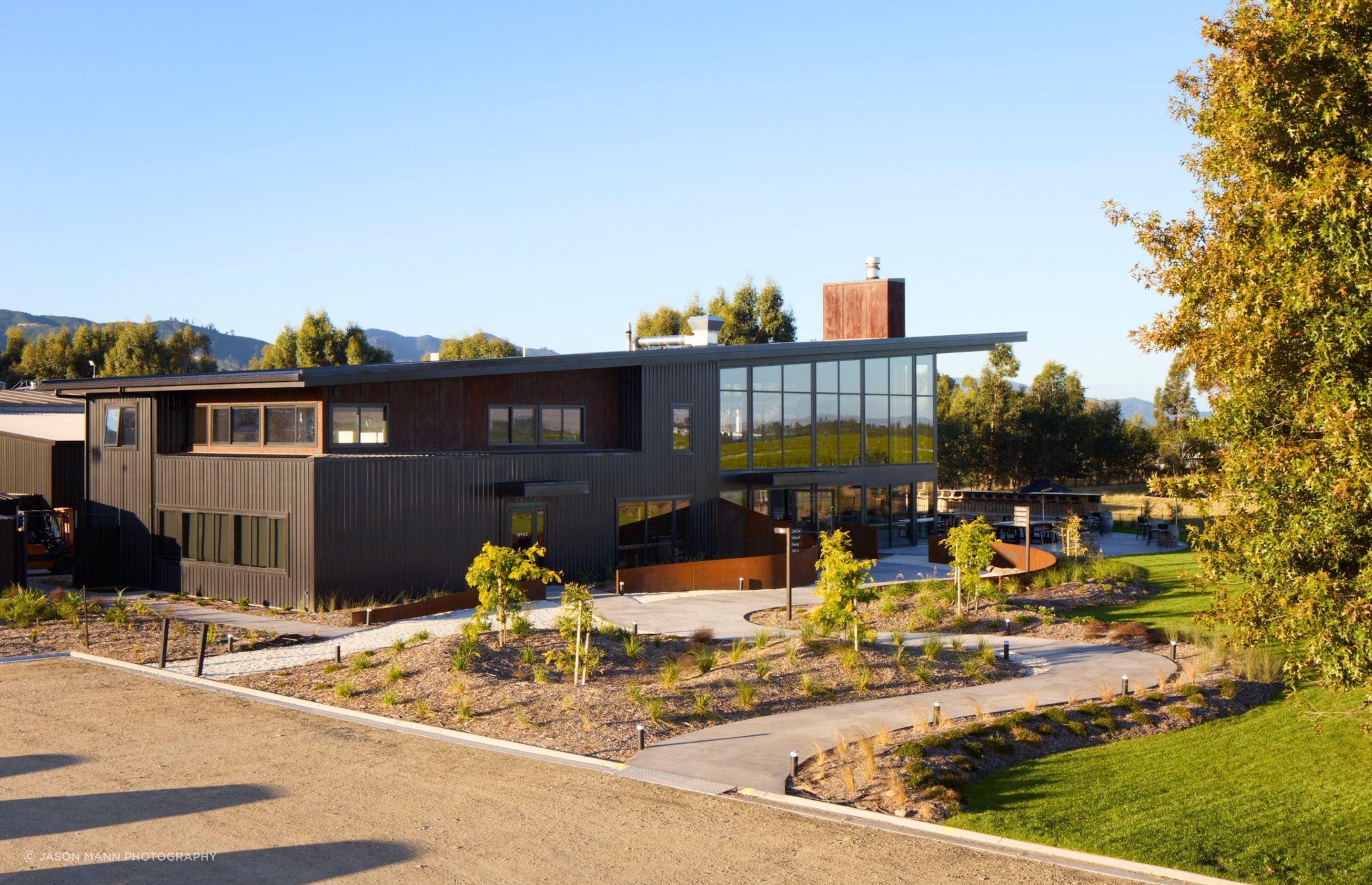 A two-storey, rectangular form meets a long, monopitched roof and an industrial chimney. A meandering path winds up towards curved Cor-Ten steel walls, referencing the braided patterns of the land whilst revealing different perspectives of the surrounding vineyards.