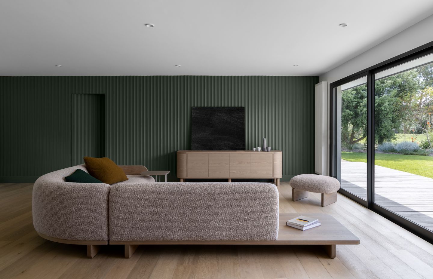 Grooved walls in a bottle green add colour and interest to the minimalist living room.