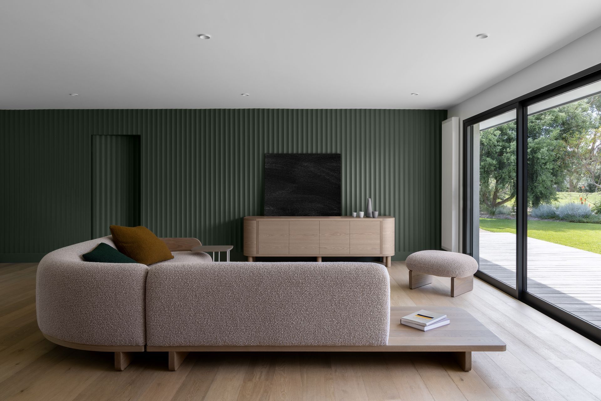 Grooved walls in a bottle green add colour and interest to the minimalist living room.