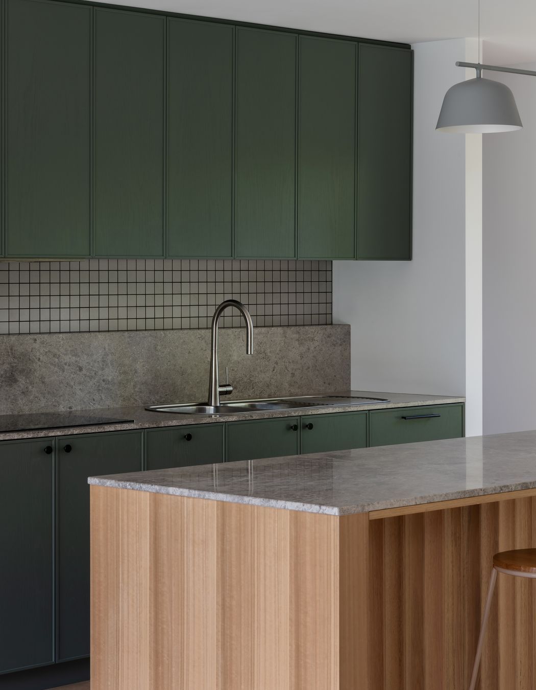 The bottle green kitchen talks to the nearby framed greenery.