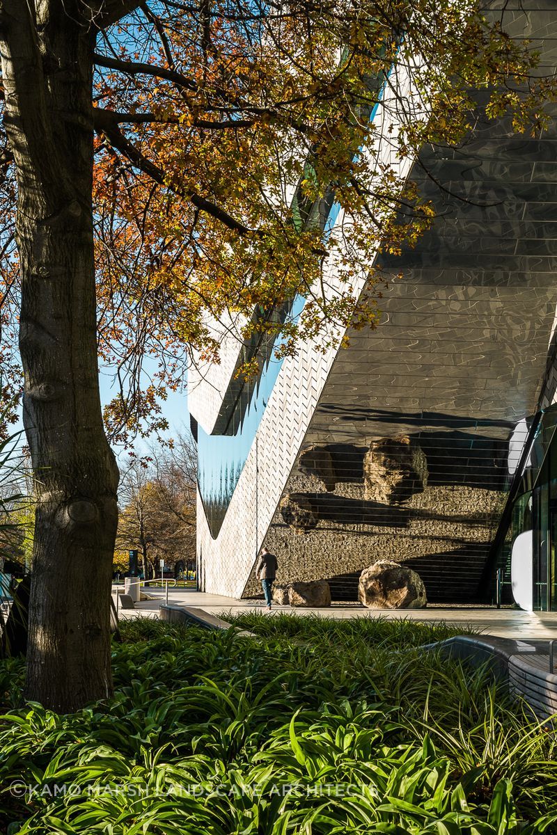 The mirrored façade reflects the patterned pavers at the building's entrance.