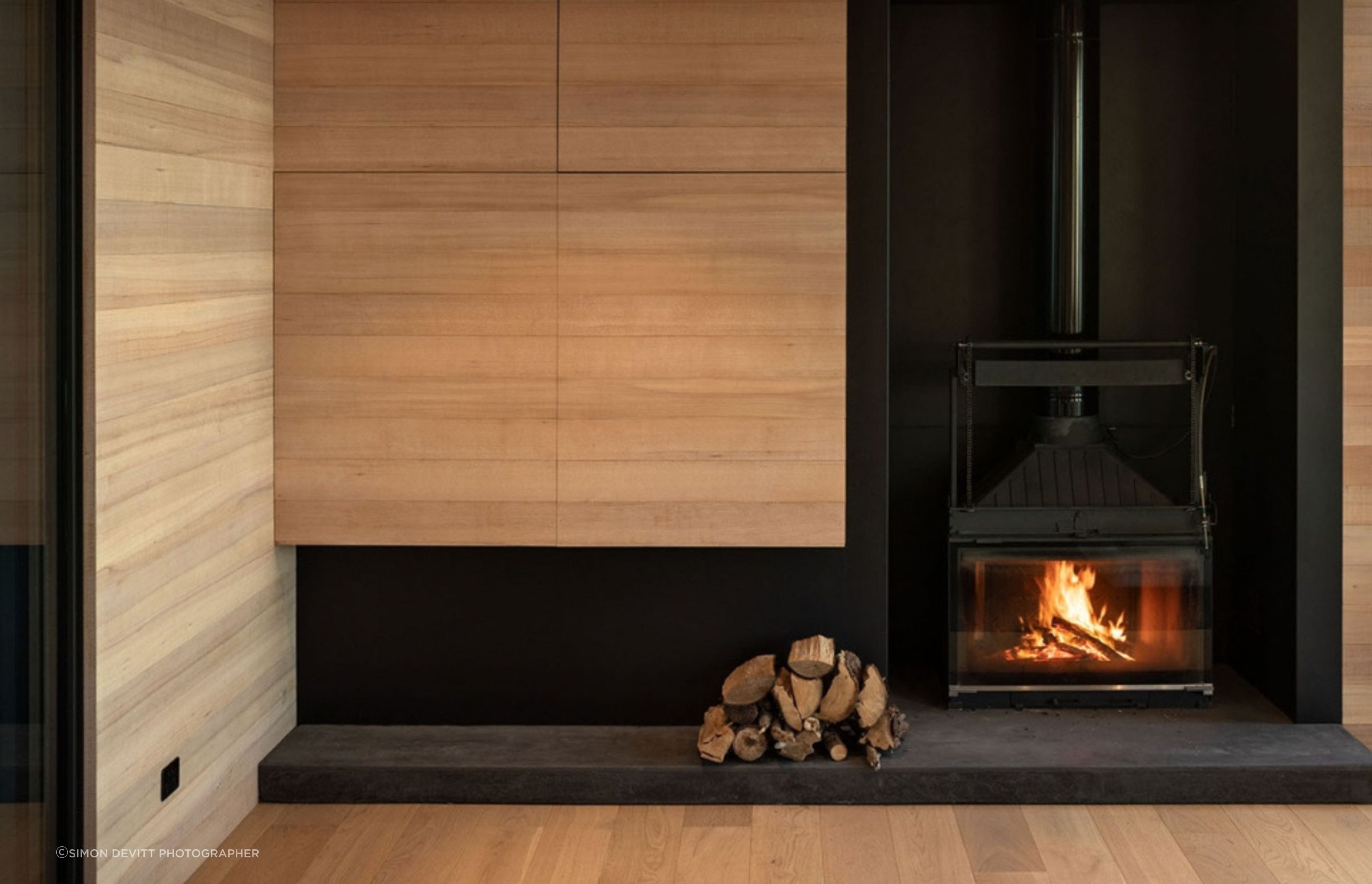 Off the dining space, the living area features plush seating, a wood-burning fireplace, and a television hidden in the cabinetry. 