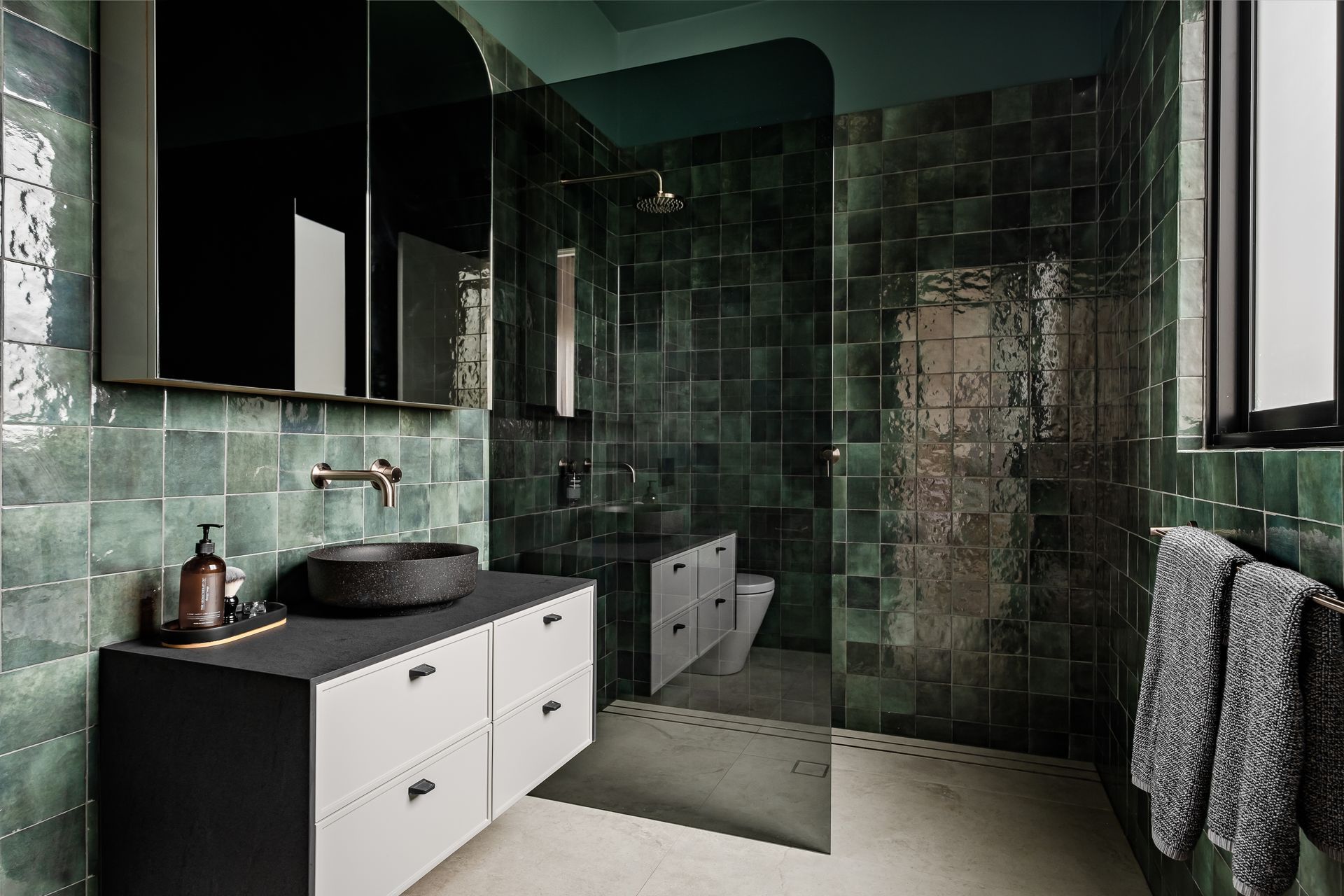 The green tiles in the bathroom create a rich and luxury palette and were chosen for the clients' love of green.