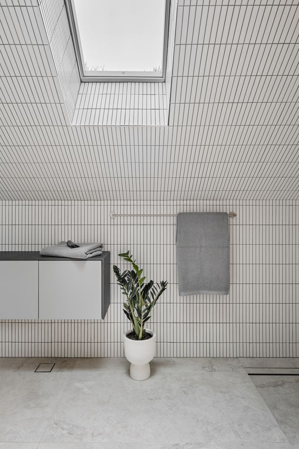 The upstairs bathroom is light and airy, featuring white finger tiles and skylights.