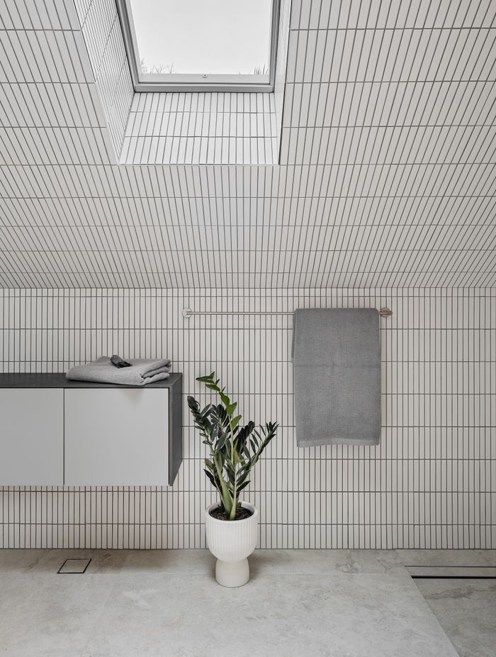 The upstairs bathroom is light and airy, featuring white finger tiles and skylights.