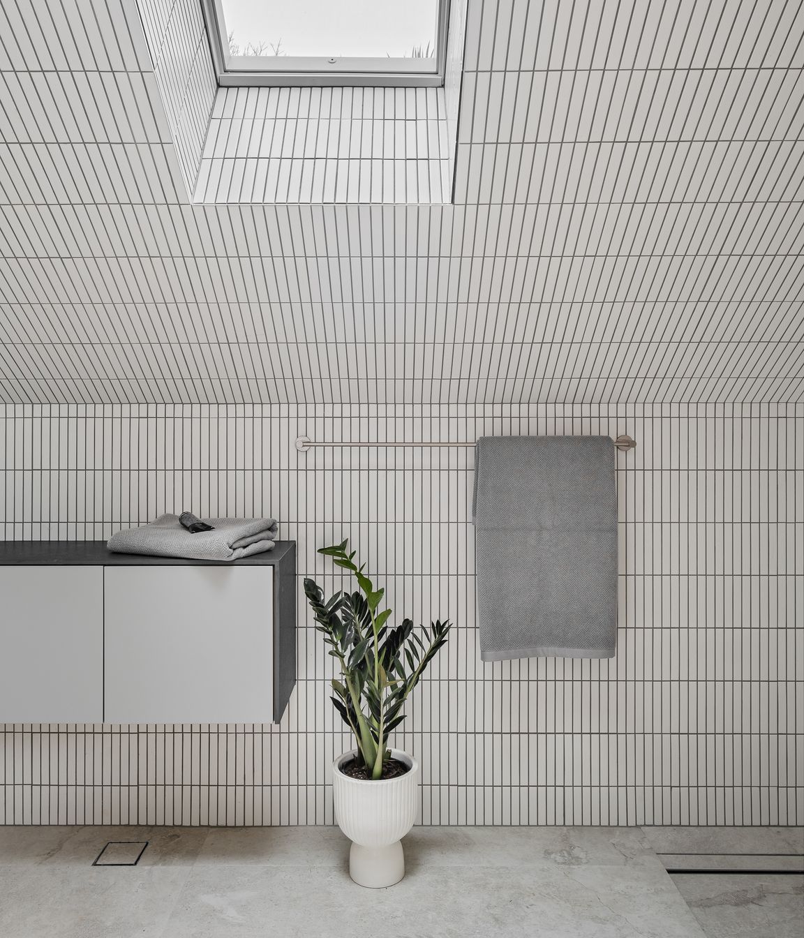 The upstairs bathroom is light and airy, featuring white finger tiles and skylights.