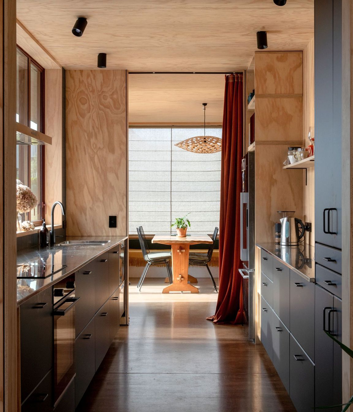 The galley-style kitchen with living areas at both ends. The pendant light is Flax by David Trubridge, and the flooring is Meranti plywood.