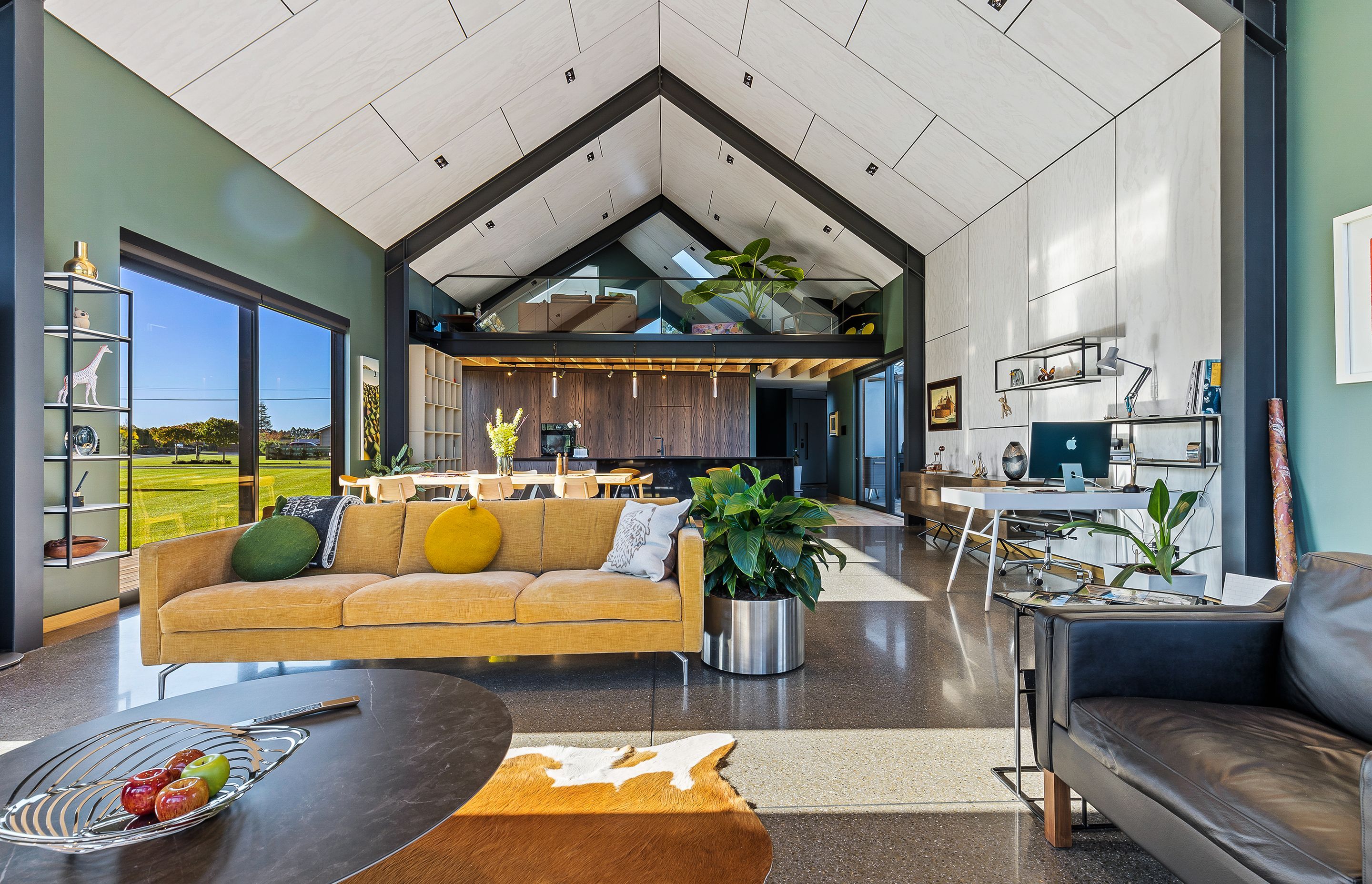 The plywood ceiling with shadow detailing extends down a section of wall in the open-plan dining and living area.