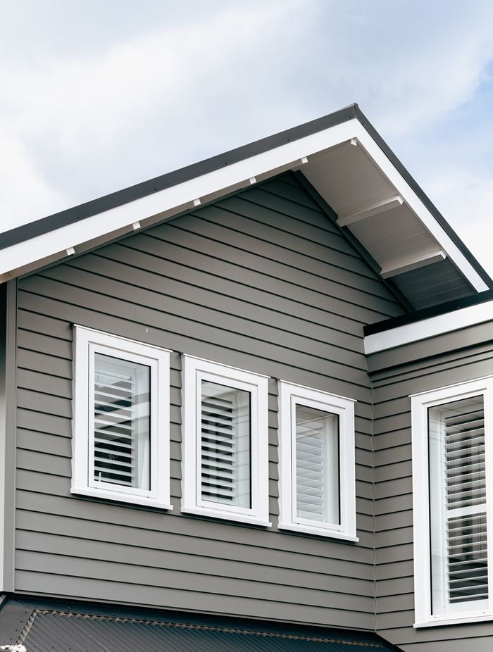 The weatherboard cladding contrasts sharply against the white joinery and soffit details.