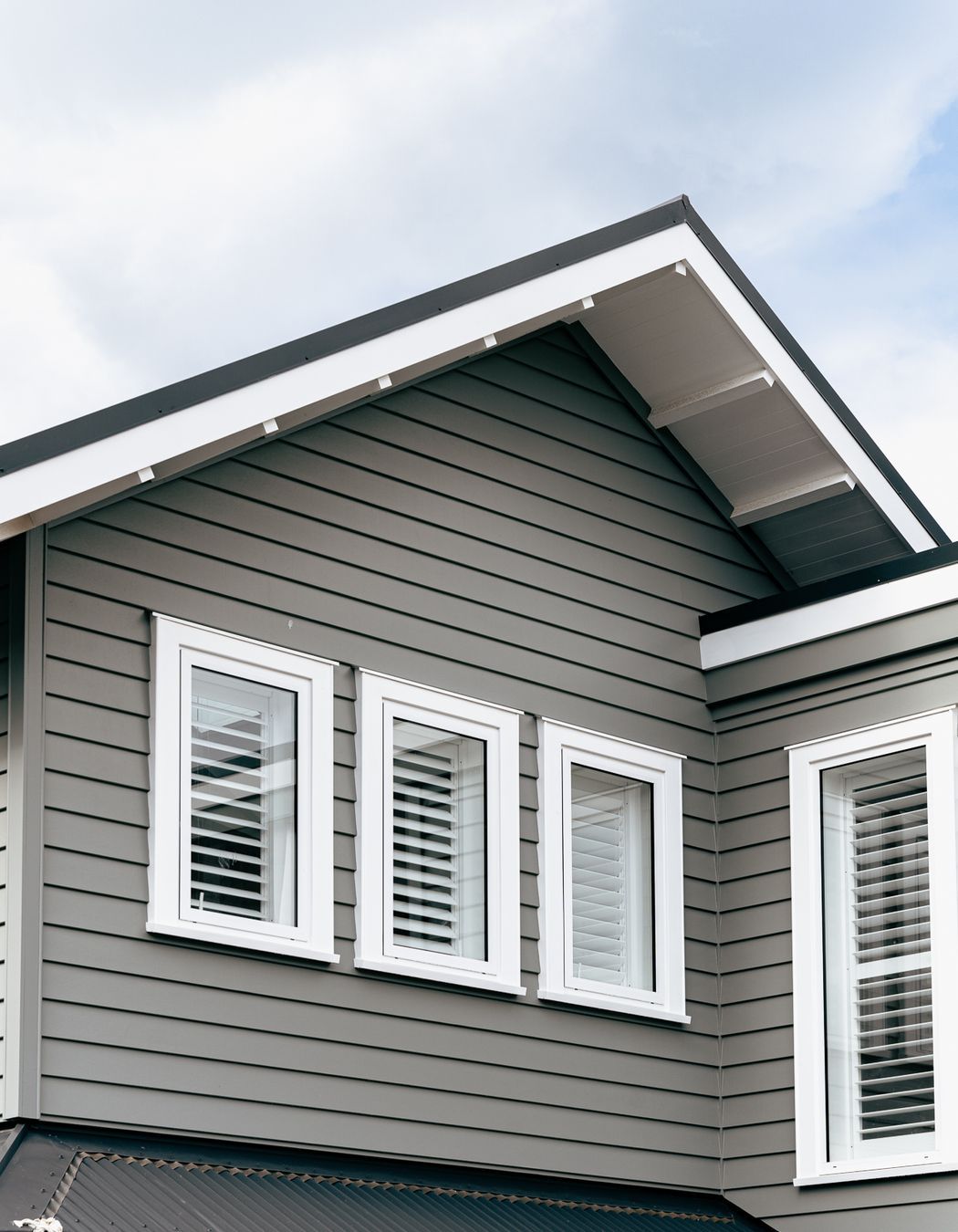 The weatherboard cladding contrasts sharply against the white joinery and soffit details.